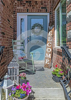 Vertical Cozy home entrance with flowers blue door sidelight and wreath at the portico