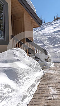 Vertical crop Stone brick pathway and stairs leading to home entrance amid deep layer of snow