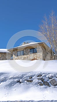 Vertical crop Stone home with snowy hip roof on a hill in Park City Utah viewed in winter