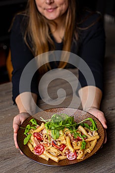 Vertical cropped woman in black outfit holding juicy, ready to eat, fresh organic pasta with basil, sauce, meat, tomato