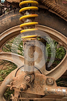 Vertical CU of muddy weathered grungy rear wheel and shock of light motorcycle in Asia