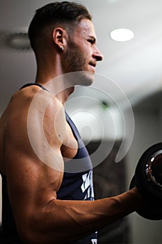 Vertical detail of a man`s arm performing biceps exercise in the gym