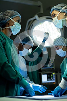 Vertical of diverse female surgeons in discussion in operating theatre during operation