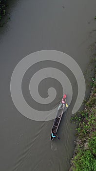 Vertical drone footage of small fishing boats floating on the river in the forest