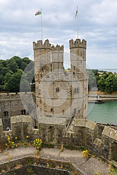 Vertical drone shot of the Caernarfon Castle in Wales with flags on its top