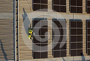 Vertical of drone view of two technician workers use laptop and tablet to check and maintenance solar cell panels on rooftop of