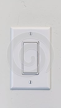 Vertical Electrical rocker light switch with flat broad lever on white interior wall