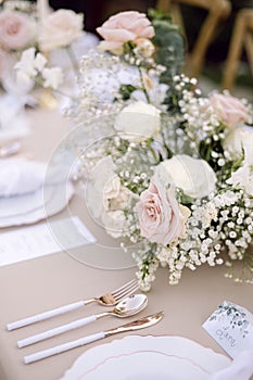 Vertical of elegant and modern wedding table setting with pink and beige flowers.