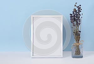 Vertical emply spring white photo frame mockup on a blue background with lavender flowers