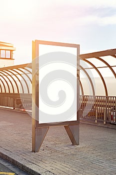 Vertical empty billboard placeholder template on the city bus stop outdoor, information banner template, space for mockup layout.