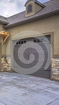 Vertical Exterior of a home with view of gray double garage doors and stone wall photo