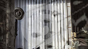 Vertical fabric white blinds on the window with the sun. Background and texture. Abstract pattern and frame. Stripes and