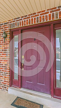 Vertical Facade of a home with a red front door and reflective sidelights and windows