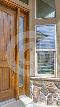 Vertical Facade of a home with shiny brown wooden front door and sidelight