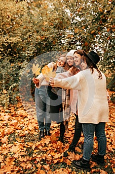 Vertical female friends company team students, spending time together, holding leaves, laughing in autumn golden nature