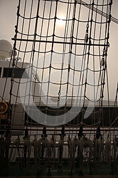 A vertical filled frame wallpaper photo of a net on a mast of a tall ship with plaited ropes and forming unordinary lines and photo