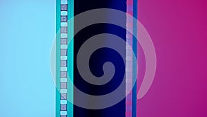Vertical film strip on a blue and pink background, close up. 35mm film slide frame. Long, retro film strip frame. Copy