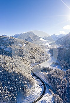 vertical format winter picture with road to the village of heiterwang in tyrol with wooded mountains