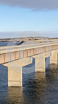 Vertical frame Beam bridge with deck supported by abutments or piers spanning over blue lake