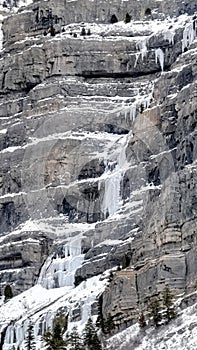 Vertical frame Bridal Veil Falls in Provo Canyon with snow ice and evergreen trees in winter