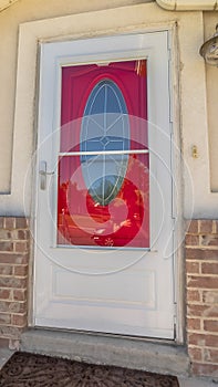 Vertical frame Exterior of a home with decorative oval glass paned vibrant red front door