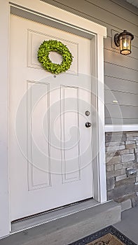 Vertical frame Facade of a home with a simple wreath hanging on the white wooden door