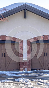 Vertical frame Facade of a residential garage with gable roof and two hinged wooden doors