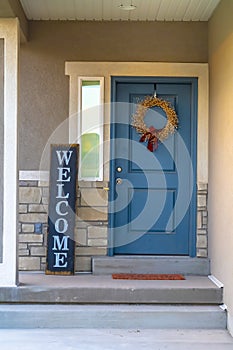 Vertical frame Golden wreath on the blue front door of a house with concrete and stone wall