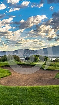 Vertical frame Hole filled with sand amid a grassy terrain against home lake mountain and sky