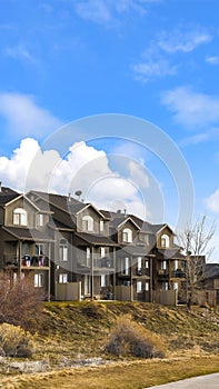 Vertical frame Houses with balconies and arched windows against blue sky with puffy clouds