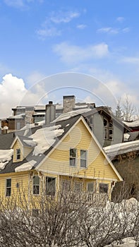 Vertical frame Houses on snow covered ground against blue sky with puffy clouds in winter