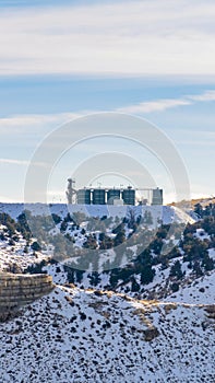 Vertical frame Industrial building on top of a rugged snowy mountain against cloudy sky