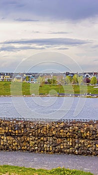 Vertical frame Lake with bank of stone and arched bridge under sky filled with clouds