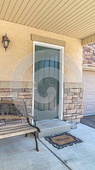 Vertical frame Old porch bench against stone brick wall of home with green wood front door