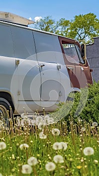 Vertical frame Old van parked in front of a home under blue sky with clouds on a sunny day