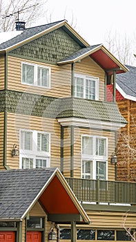 Vertical frame Selective focus of townhome with balcony and snowy roof against cloudy sky