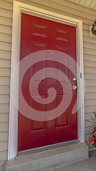 Vertical frame Shiny red wooden front door of a home with wicker chairs on the sunlit porch