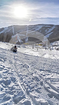 Vertical frame Ski resort on a mountain covered with snow under blue sky and bright sun