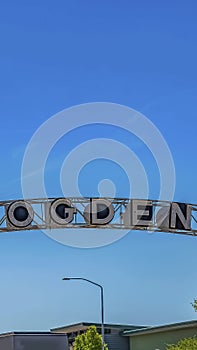 Vertical frame Welcome arch at the city of Ogden in Utah against lush treetops and blue sky