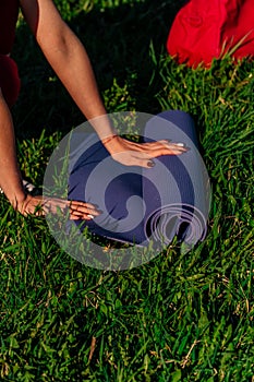 Vertical frame womens hands spread out a sports mat on green grass in the park concept of outdoor workouts