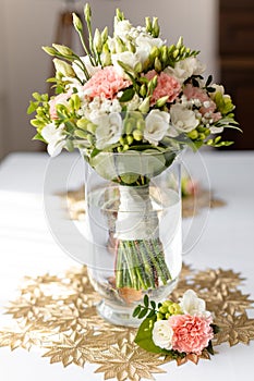 Vertical of fresh flower bouquet in transparent water vase on table with print tablecloth. Wedding floral arrangement