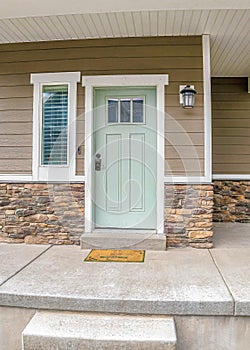 Vertical Front door and sidelight against brick wall and wood siding of home with porch