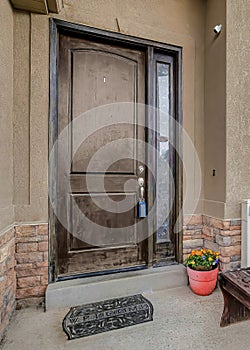 Vertical Front door with sidelight of house with bench and potted flowers at the portico