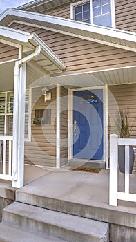 Vertical Front view of a home with cozy porch and glass paned bright blue front door