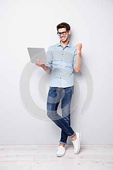 Vertical full length body size photo of cheerful positive handsome attractive guy having succeeded in project writing