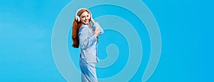 Vertical full-length portrait sassy and coquettish, flirty redhead woman in cute pyjama, dancing listen music in big