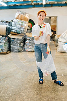 Vertical full length portrait of smiling woman volunteer holding in hands used plastic objects and looking at camera in