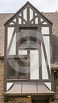 Vertical Gabled dormer with decorative windows against brick wall and roof of building