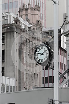 Vertical grayscale of an old street clock hanging on a wall of an office building