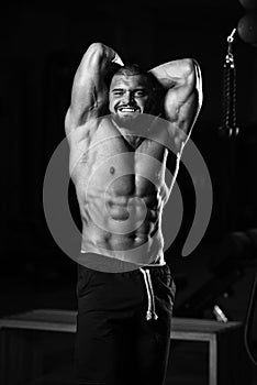 Vertical grayscale shot of a healthy young Caucasian man posing in the gym and flexing his muscles